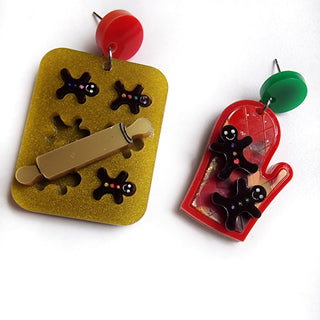orecchini in plexiglass taglio laser natalizi con teglia da forno dorata e biscotti omino in cioccolato e guanto da forno rosso in plexiglass riciclato