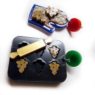 orecchini in plexiglass taglio laser natalizi con teglia da forno nera e biscotti omino in cioccolato e guanto da forno blu in plexiglass riciclato