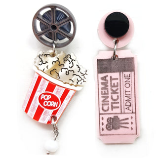 Orecchini in plexiglass con ticket rosa, pellicola cinematografica e bicchiere di pop corn rosso